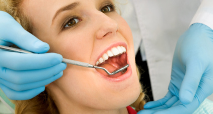 Close-up of young woman during inspection of oral cavity with help of hook and mirror